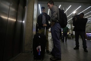 U.S. journalist Glenn Greenwald stands with his partner David Miranda as they wait for the lift at Rio de Janeiro's International Airport